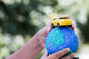 Eco friendly Save world concept. Yellow car and Hands holding Model globe clay with radar Natural background. Ideas of earth maintenance by reducing energy consumption, Travel around the world