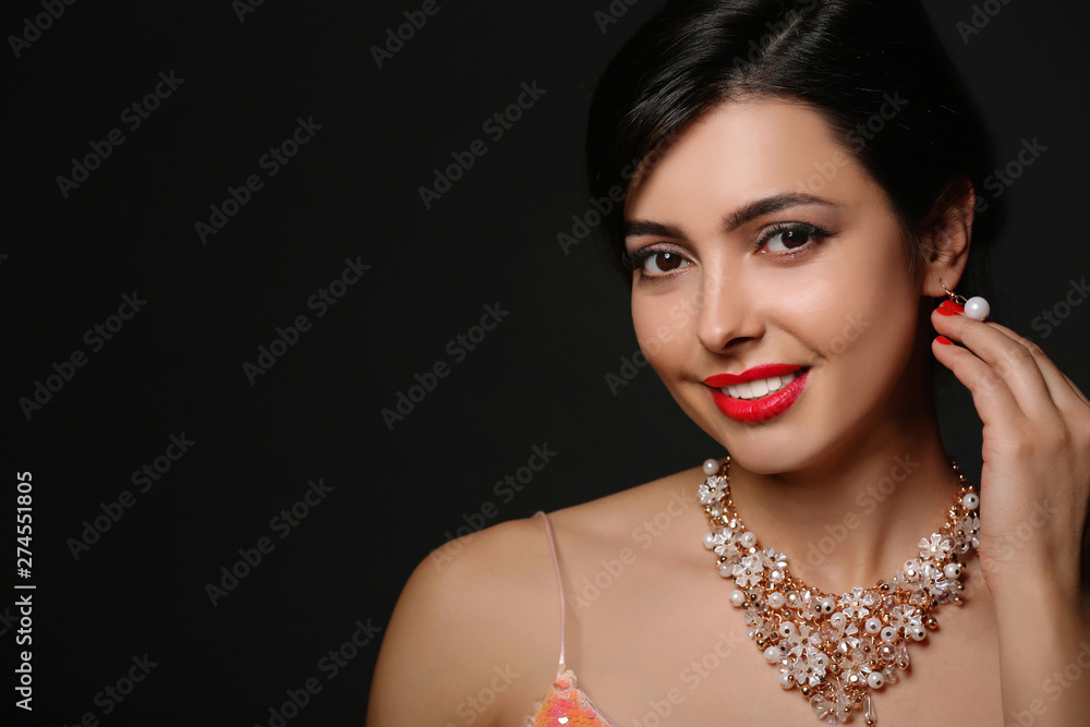 Poster beautiful young woman with elegant jewelry on dark background. space for text