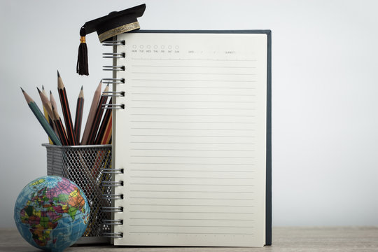 Empty notebook mockup for your image text with pencils, world globe, graduation hat on white background. Concept of global business study abroad educational. Back to School.