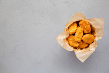 Chicken nuggets in a paper box on a concrete background. Overhead, from above, flat lay. Copy space.