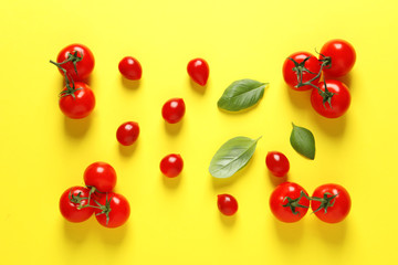 Flat lay composition with ripe cherry tomatoes and basil leaves on color background