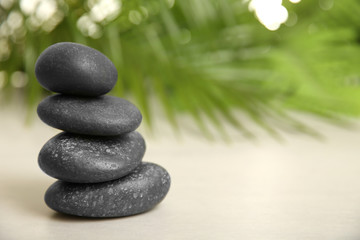 Stack of spa stones on table against blurred background. Space for text