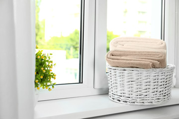 Basket with clean soft towels on window sill. Space for text