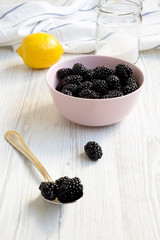Ingredients for blackberries jam: berries, lemon, sugar on a white wooden surface. Close-up.