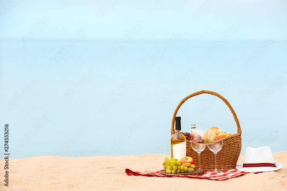 Canvas Prints Wicker basket with food and wine on blanket near sea, space for text. Summer picnic