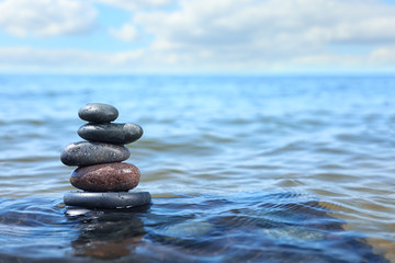 Stack of stones in sea water, space for text. Zen concept