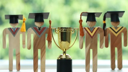 Education graduation in achievement success concept: Golden trophy cup winner or intelligence with graduate people on blur background. Congratulation in university and success prize awards theme ideas