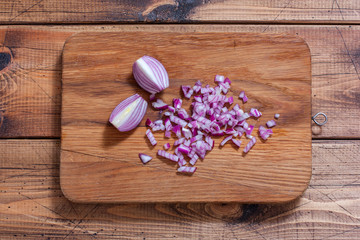 chopped red onions on a wooden board, top view, horizontal