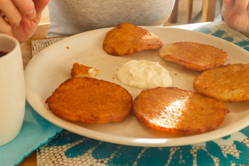 Delicious potato pancakes on plate with sour cream