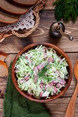 Salad with fresh cabbage and smoked sausage on a wooden table, top view, selective focus
