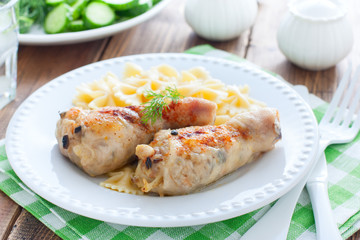Chicken legs stuffed with champignons on a white plate with pasta, horizontal