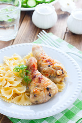 Champignons stuffed chicken drumsticks on a white plate with pasta, selective focus