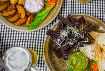 bread croutons with garlic and other snack with glass of beer on table in bar