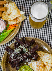 bread croutons with garlic and other snack with glass of beer on table in bar