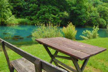 Fototapeta premium Home made wooden bench and table next to very scenic and green river bank