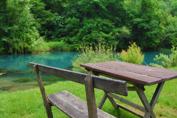 Home made wooden bench and table next to very scenic and green river bank
