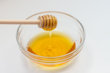 honey dripping from dipper on white background