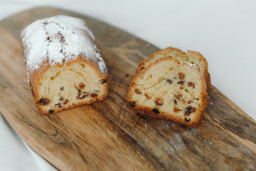 Raisin cake, dusted with icing sugar. Cupcake with raisins on a wooden board