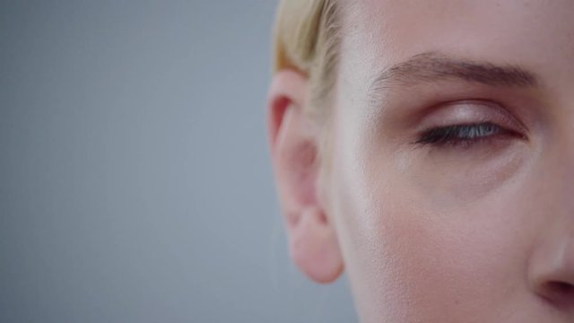 Close-up portrait of playful blonde girl rolling her blue eyes round. Macro view on pretty female face.
