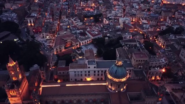 drone approaching from above Palermo Cathedral with beautiful evening lights, Sicily, Italy. Built in arab-norman style, it is a UNESCO World Heritage Site
