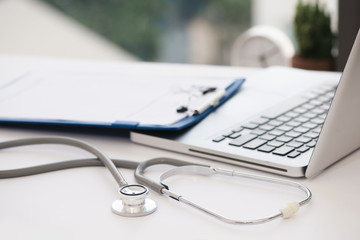 Stethoscope, prescription medical form lying on glass table with laptop computer. Medicine or pharmacy concept. Medical tools at doctor working table