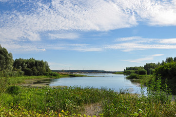 Wide blue river is slow flowing. Summer. Sunny weather and white sand. green trees far away