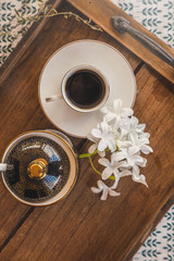 Black Coffee Cup on wooden tray top view with white flowers