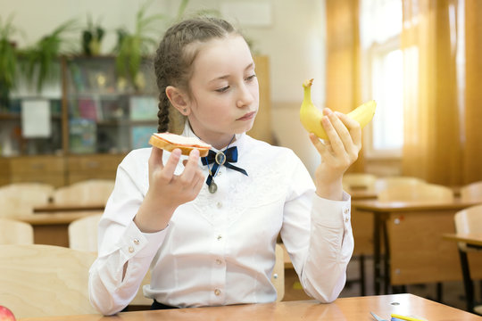 School girl on a diet makes a choice between fruit and a harmful sandwich.