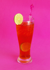 Glass of iced lime tea on pink background