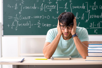Young male student mathematician in front of chalkboard 