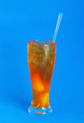 Glass of iced peach tea on blue background
