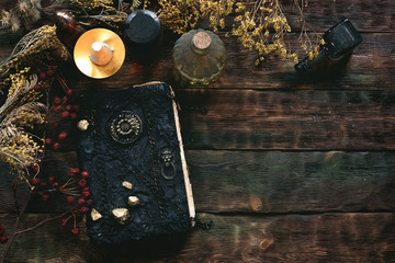 Magic recipe book of witch doctor, dried herbs and a magic potion on a wooden table. Witchcraft...