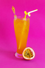 Glass of passion fruit juice on pink background