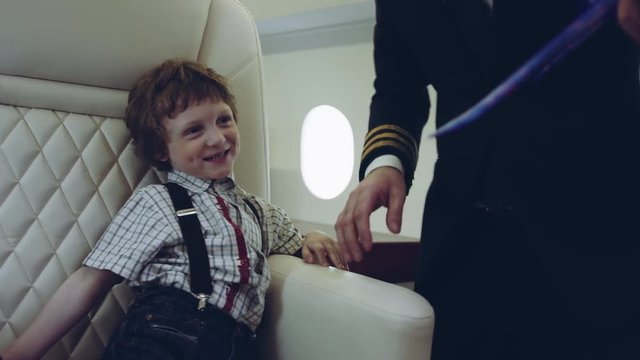 Pilot carries boy playing with blue plane toy, imagination dreaming of being a pilot future, on a boarder of private jet plane. RED HELIUM.