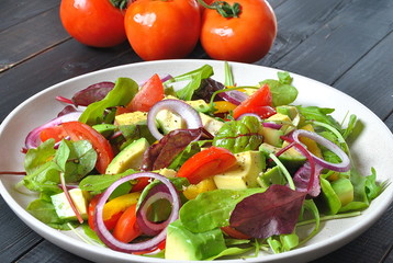 Avocado salad with shrimps, cherry tomatoes, arugula beet leaves, red onion, yellow sweet pepper. Healthy lunch plate with vegetables and shrimps