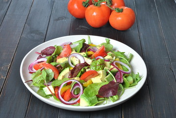 Avocado salad with shrimps, cherry tomatoes, arugula beet leaves, red onion, yellow sweet pepper. Healthy lunch plate with vegetables shrimps