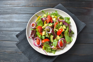 Avocado salad with shrimps, cherry tomatoes, arugula beet leaves, red onion, yellow sweet pepper. Healthy lunch plate with vegetables shrimps