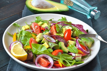 Avocado salad with shrimps, cherry tomatoes, arugula beet leaves, red onion, yellow sweet pepper. Healthy lunch plate with vegetables and shrimps
