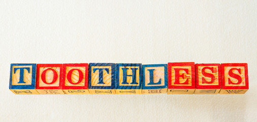 The term toothless visually displayed on a clear background using colorful wooden blocks image in...