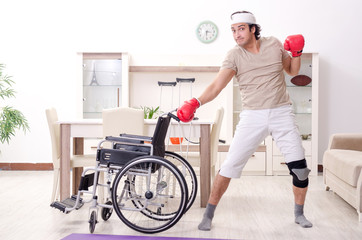 Injured young man doing exercises at home 