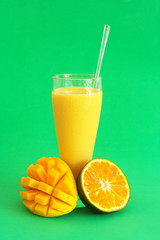 Mango with orange smoothie with mango and fruit on green background