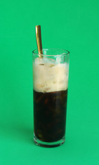 Vietnamese iced coffee in glass with golden spoon on green background