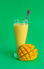 Mango milkshake and mango fruit on green background
