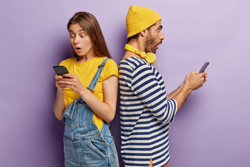 Shocked emotional guy and young woman stand turned backs, surprised with bad news, type various...
