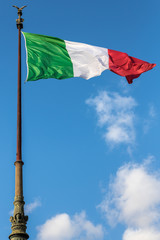 Italian flag waving in Rome, Italy with blue sky and white clouds in the background