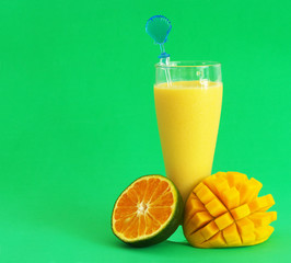 Mango and orange fruit smoothie with room for text on green background