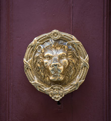 Old golden iron lion head door knocker on a wooden door. Mdina, Malta