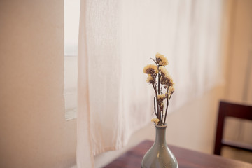 small bouquet of dry flower in single vase on old wooden table and chair