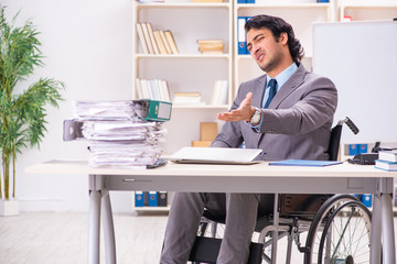 Young handsome employee in wheelchair at the office 