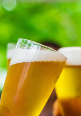 Close-up view of a three glass of beer in hand. Beer glasses clinking at outdoor bar or pub